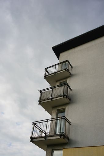 A low angle shot of balconies of an apartment building against a cloudy sky