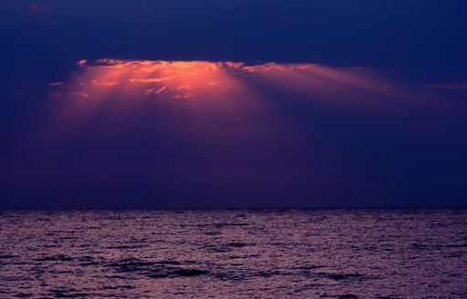 A mesmerizing sunset scenery over the sea with the sunbeams shining through the clouds