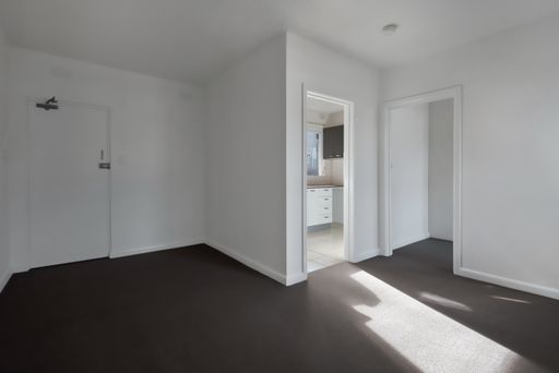 A corner of an empty new room with white walls, doors, and black floor