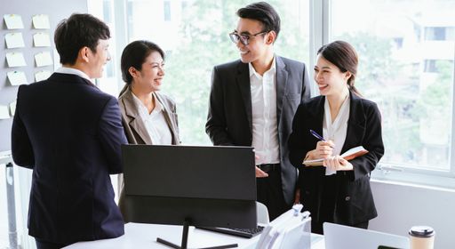 A young Vietnamese business team in suits happily discussing the project in the office