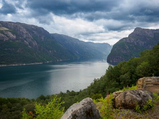 A breathtaking view of Stavanger Fjord surrounded by mountains under a vibrant cloudy sky in Norway