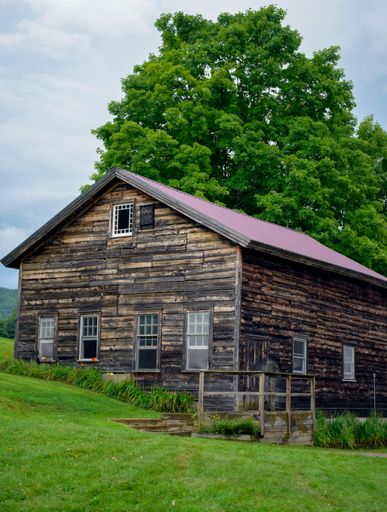 A rustic barn in a rural setting with weathered wood and a scenic backdrop