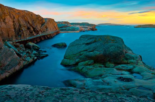 A  beautiful view of the rocks and the hills surrounding the water during sunset