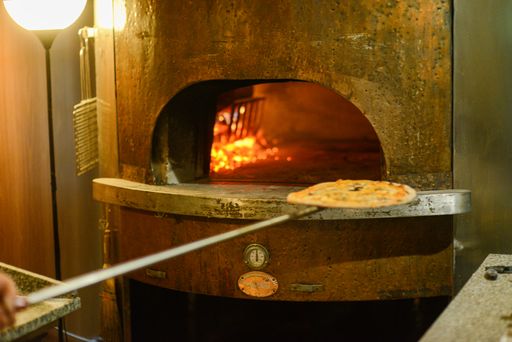 A closeup shot of pizzas inside a traditional copper oven fueled by wood in Mignano, Italy