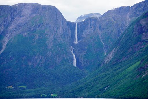 A stunning view of a tall waterfall cascading down a mountain in a lush green valley.