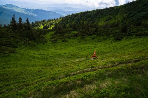 A great wide natural shot of Caucasian (White) girl with red outfit doing sport in a green place in Ukraine