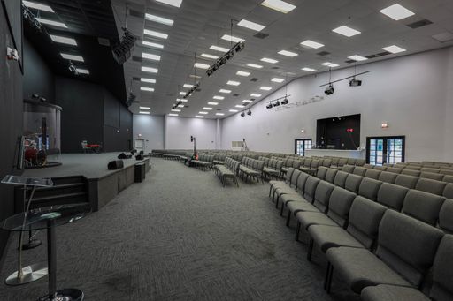 Interior of a modern church auditorium with rows of empty seats and a stage setup.