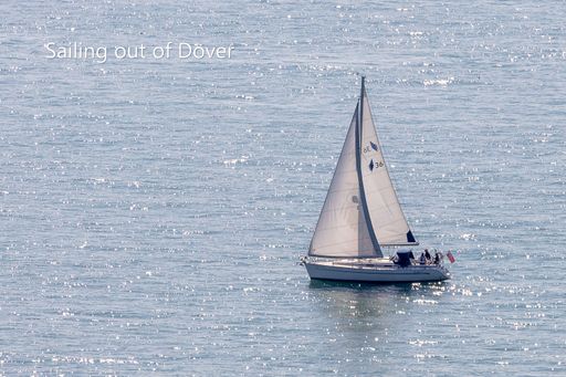 A sailboat gliding on the calm waters near Dover on a sunny day.