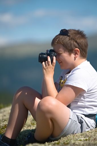 A vertical shot of a young Caucasian boy looking away from the camera, taking a picture