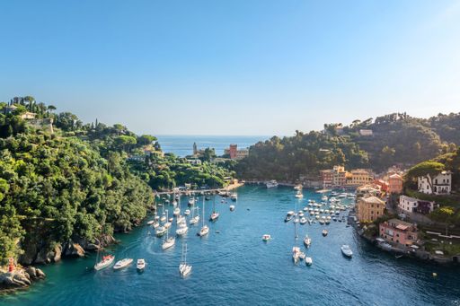 A picturesque view of Portofino, Italy, with boats docked in the harbor and colorful buildings on a sunny day.