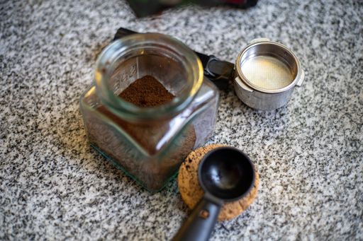 the ground coffee in a jar next to the tools for making coffee