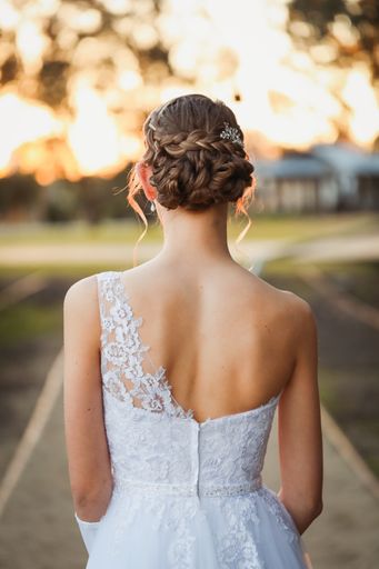 A vertical shot of a young female in a bridal dress with hair done outdoors