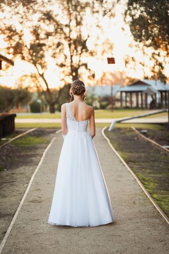 A vertical shot of a young female in a bridal dress with hair done outdoors