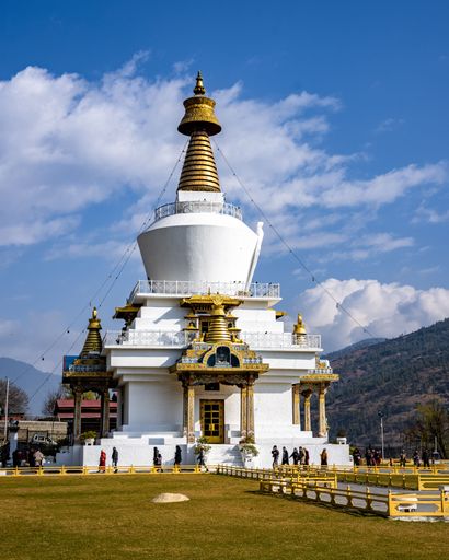 The Memorial Stupa Chorten, a Tibetan Buddhist temple in Thimphu, Bhutan, surrounded by mountains and blue skies.