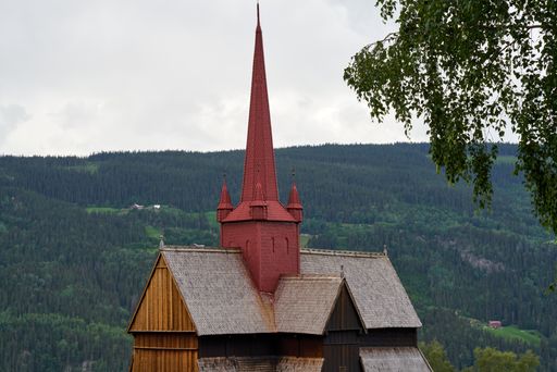 A closeup shot of Ringebu stave church tower and mountains in the background