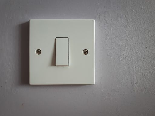 A closeup shot of a white light switch on a white wall