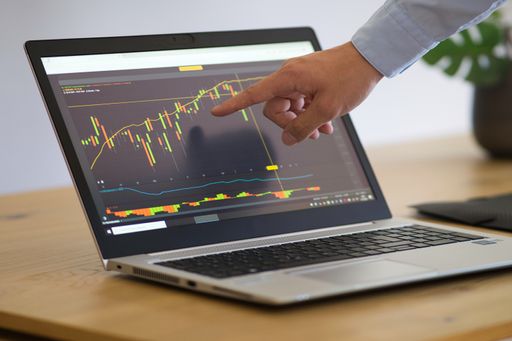 Man in business shirt pointing his finger at the stock price on the laptop