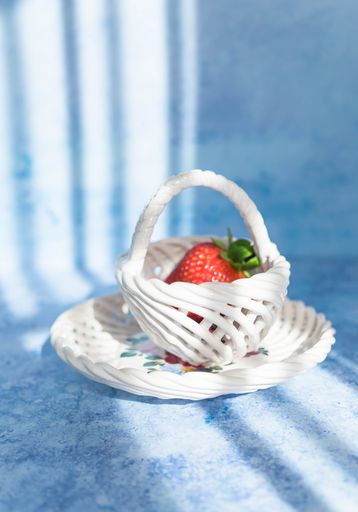 A vertical shot of a fresh strawberry in a white small basket