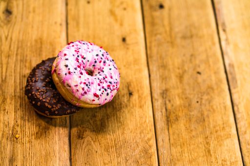 A high angle shot of colorful donuts with glazed sprinkles on wooden table