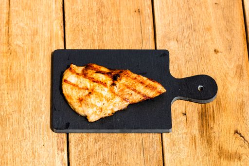An overhead shot of grilled steak on small black chopping board