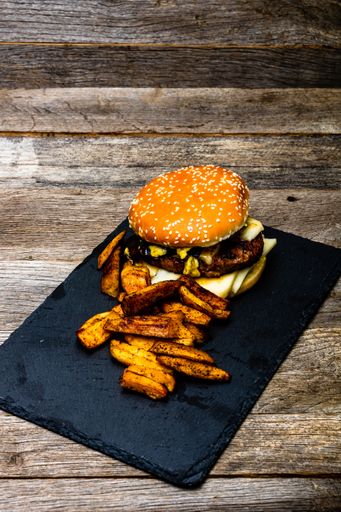 A high angle shot of homemade fresh tasty cheeseburger and fried potatoes on a wooden table