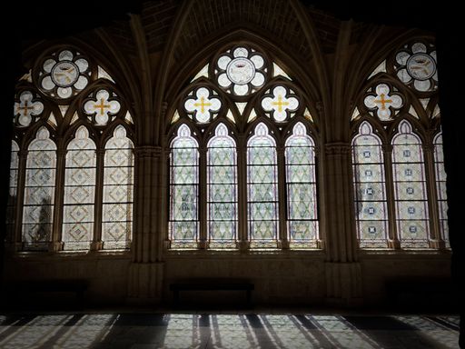 Stained glass windows with arches and columns, crossed by the sun, casting shadows in the corridors of the Burgos Cathedral, in Spain