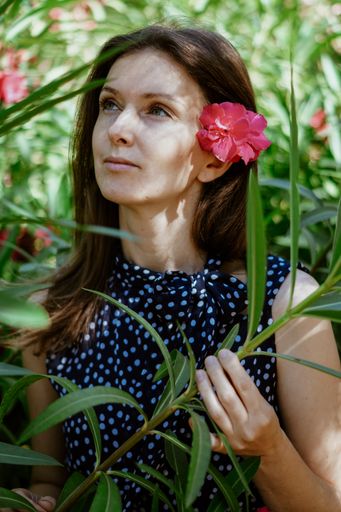 A vertical portrait of a caucasian female with a red flower in her hair