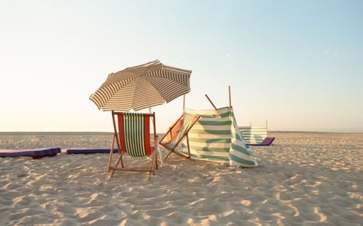 An umbrella and folding chairs on the beach under the sunlight - perfect for wallpapers