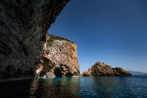 A scenic view of a beautiful seascape with a rocky cliff on a sunny day against blue sky background
