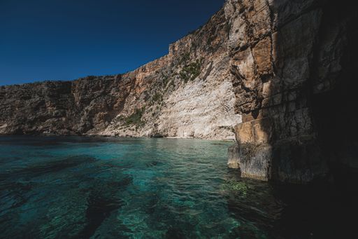 A scenic view of a beautiful landscape of a rocky shoreline with clear waters on a sunny day with blue cloudless sky