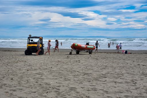 A shot of the people walking on sand in Sumner Beach during a summer day in New Zealand.