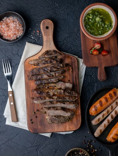 A vertical top view of a delicious steak cut into thin strips on a wooden cutting board w