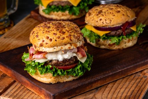 A closeup of juicy hamburgers served next to each othon two wooden boards