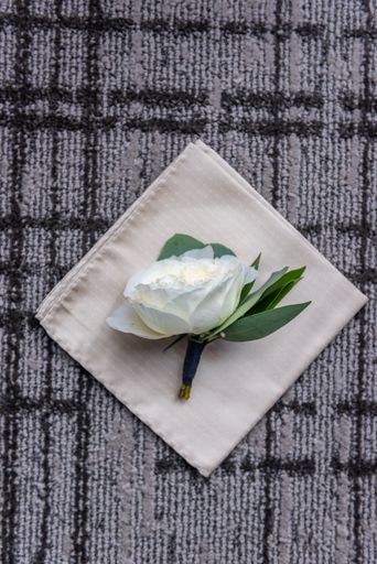 A vertical shot of a white groom's pocket flower on a white napkin