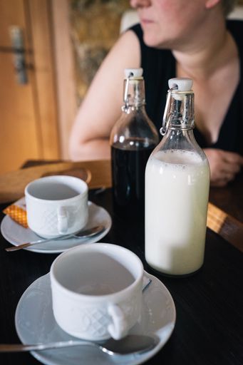 A closeup shot of coffee cups and bottles on the table with a woman sitting in the background