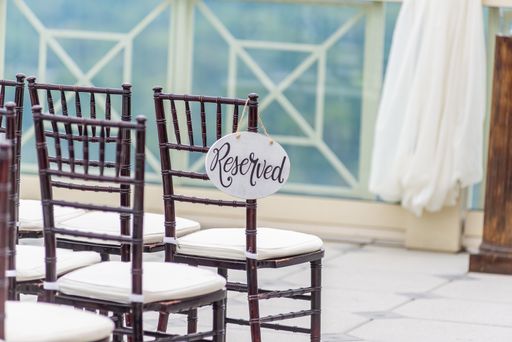 A closeup shot of wooden chairs in a ceremony hall with the tag "Reserved" hanging from one