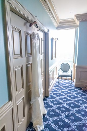 A  side shot of a bridal dressing room with a bridal gown hanging on the hanger on the door frame