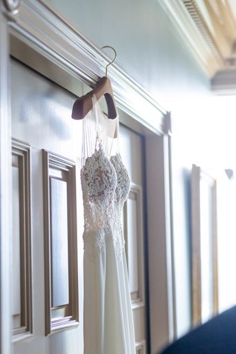 A vertical shot of a white wedding dress hanging on a hanger