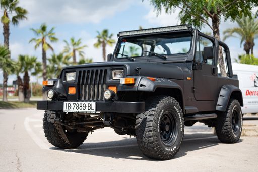 Close-up of a spectacular first generation 1987-1996 black Jeep Wrangler YJ, modified with large wheels, fenders and upper light bar