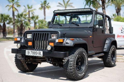 Close-up of a spectacular first generation 1987-1996 black Jeep Wrangler YJ, modified with large wheels, fenders and upper light bar