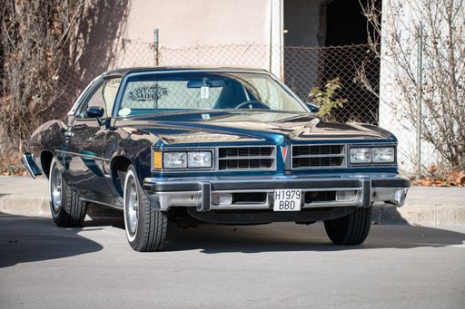 Front view of an old American car Pontiac LeMans fourth generation 1973-1977 in blue green color, parked on the street