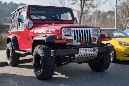 Front view of the classic red first-generation American off-road Jeep Wrangler YJ.