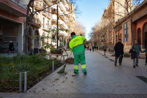 Detail of a sweeper from the city hall of Barcelona sweeping the leaves from the pedestrian street, his back is turned