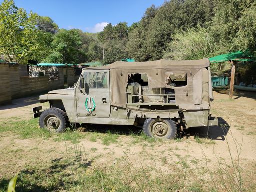 Side view of an old army Land Rover Santana Ligero with canvas roof in a military airsoft training field