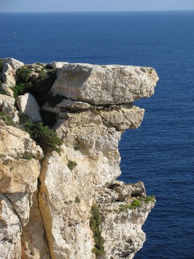 A vertical shot of the edge of a coastal cliff, made of limestone rock, along the Maltese coastline