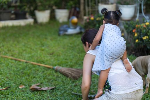 A shallow focus shot of a cute Southeast Asian girl climbing on the back of her mother