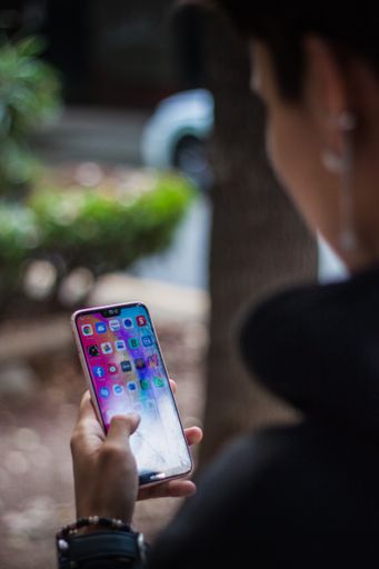 A vertical over the shoulder shot of a young boy with a smartphone in his hand