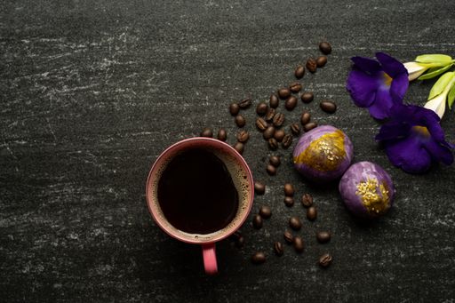 A top view of a cup of coffee on a table with beans and flowers