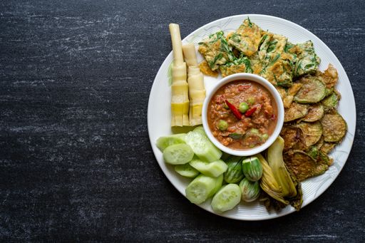 A top view of shrimp paste sauce and vegetables set on a wooden background. Traditional Thai food