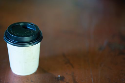 A closeup shot of a take away cup of coffee on a wooden surface